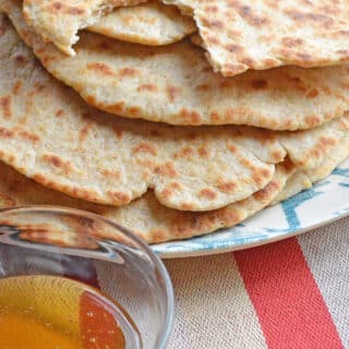 Skillet flatbread with a cut and small bowl of honey