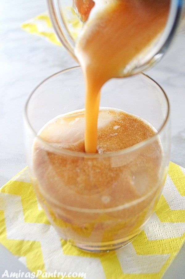 A photo showing a glass of Tamarind juice is being poured