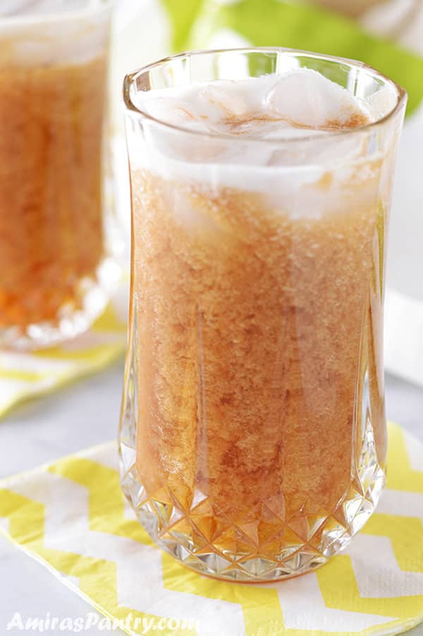 A tall glass with sweet tamarind juice with ice floating at the top.