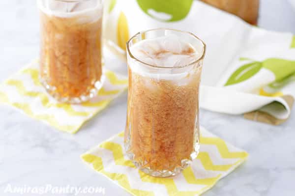 two tall cups of tamarind juice placed on yellow and white napkins.