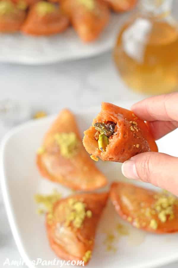 Hand holding one qatayef showing the nut mixture inside.