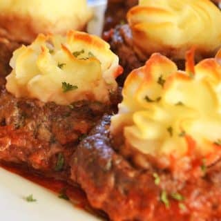 A close up of a plate of food, with meatballs and potato