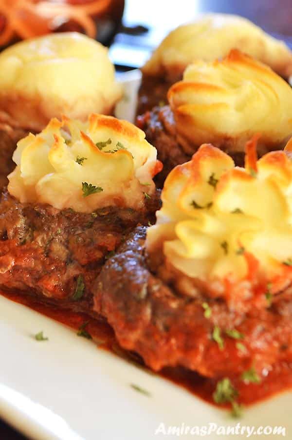 A close up of a plate of food, with meatballs and potato