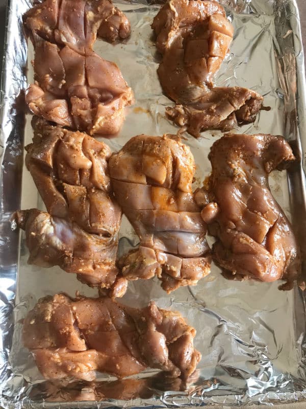 Chicken thighs marinated and arranged on a baking sheet