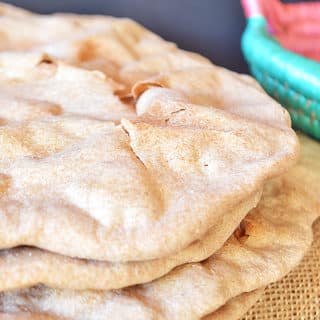 Una pila di pane piatto azzimo con una tela di iuta sotto.