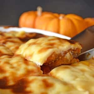 A servng spoon scooping pumpkin pie out of baking dish.