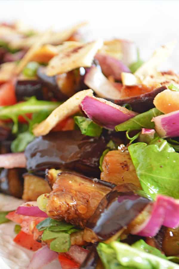 A closer look on eggplant salad showing eggplants with onion and arugula