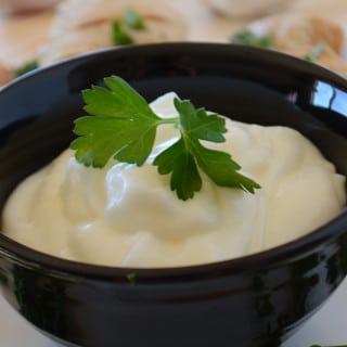 A cup of food on a plate, with Garlic dip