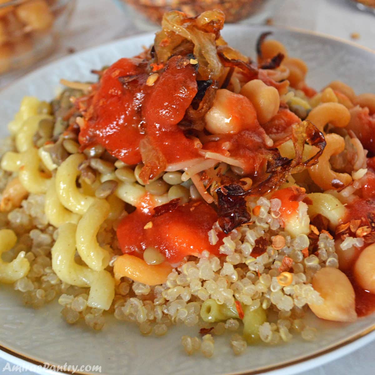 A pile of koshari made with quinoa placed on a white plate