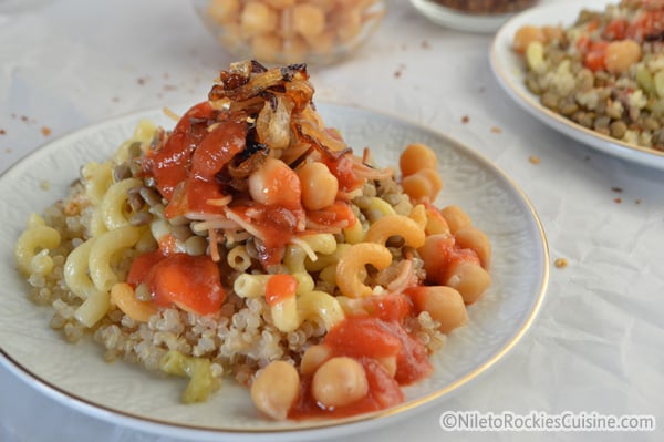 A bowl of food on a plate, with quinoa, chickpeas and rice