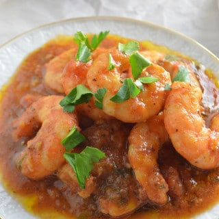 A close up of a plate with shrimp covered in sauce