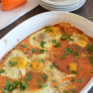 A bowl of food on a plate, with Shakshouka showing beans and eggs