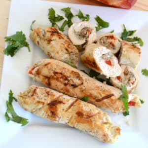 Quinoa stuffed chicken rolls on a white plate.