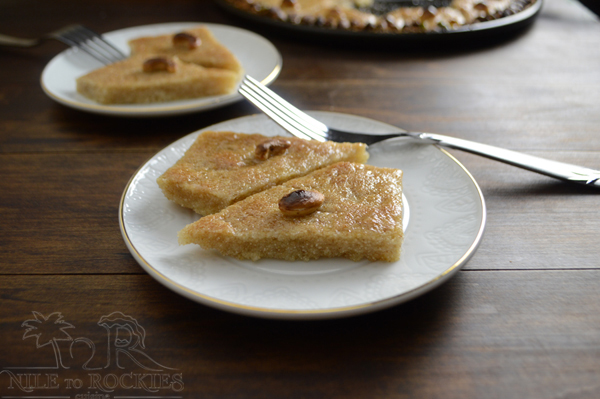 A plate of food on a table, with Basbousa and fork