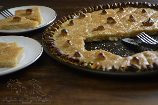 A piece of Basbousa on a plate, with Nuts