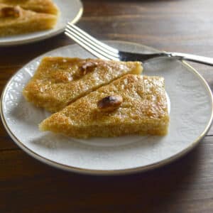 Two pieces of basbousa on a small dessert plate.