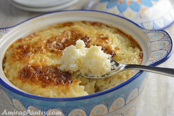 A close up of a bowl of food, with Rice pudding and spoon