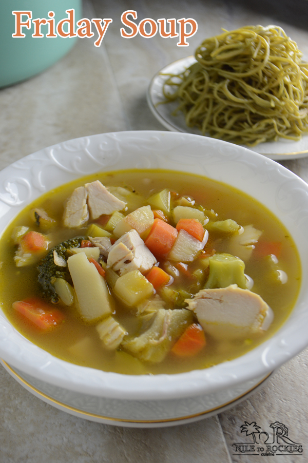 A bowl of soup on a plate, with chicken and vegetables