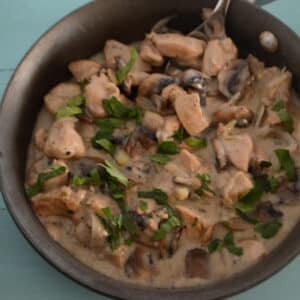 A skillet with chicken and mushroom.