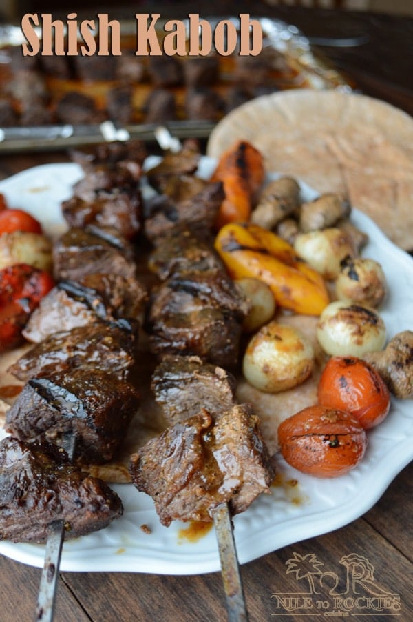 A plate of food on a table, with Shish Kabobs and vegetables