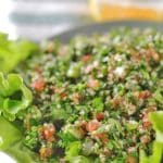 A green plate with tabouli served over lettuce leaves.
