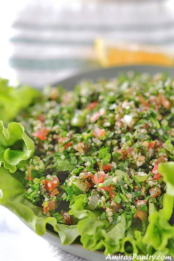 A green plate with tabouli served over lettuce leaves.