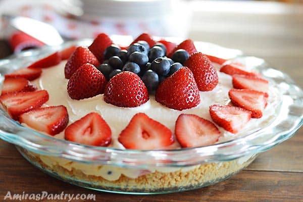 A close up of a cake with fruit in a glass bowl on top of a table