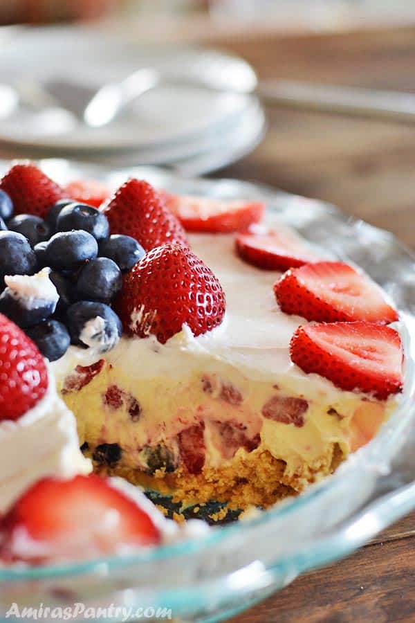 A close up of a cake with fruit in a glass bowl on top of a table