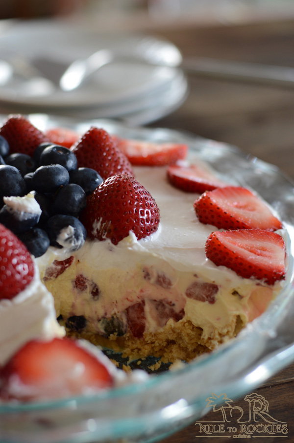 A close up of a piece of cake on a plate, with Cream and Berries