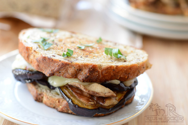 A close up of a sandwich on a plate, with Cheese and Eggplant