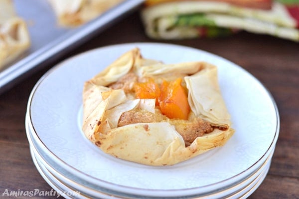 A pumpkin egg-less frangipane tart on a stack of white plates with a sheet pan on the back