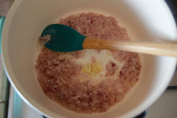 A bowl of food on a stove, with onions and spoon