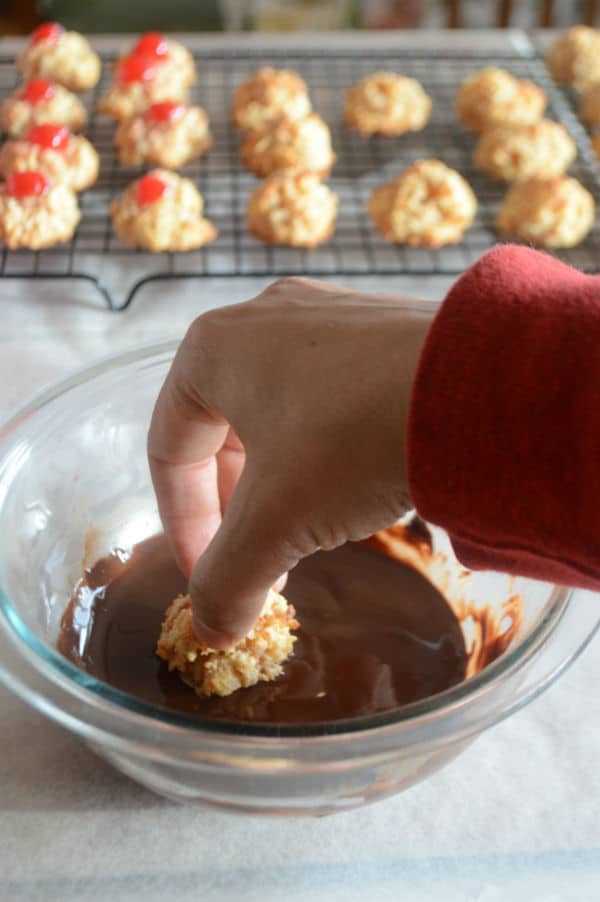 A bowl of food on a plate, with hand mixing Macaroon in chocolate