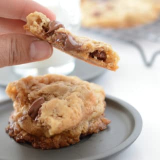 A piece of cookie on a plate, and hand holding another piece