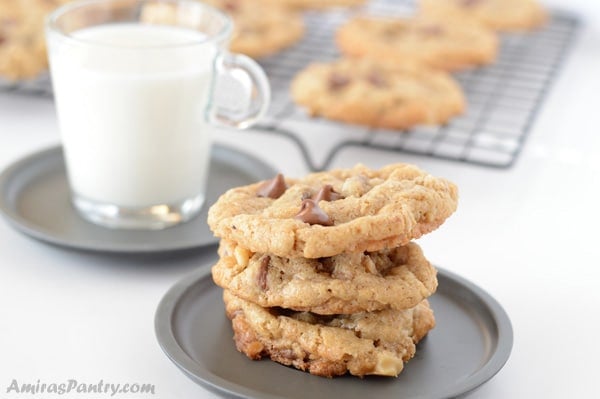 A close up of a plate of oatmeal cookies and cup of milk