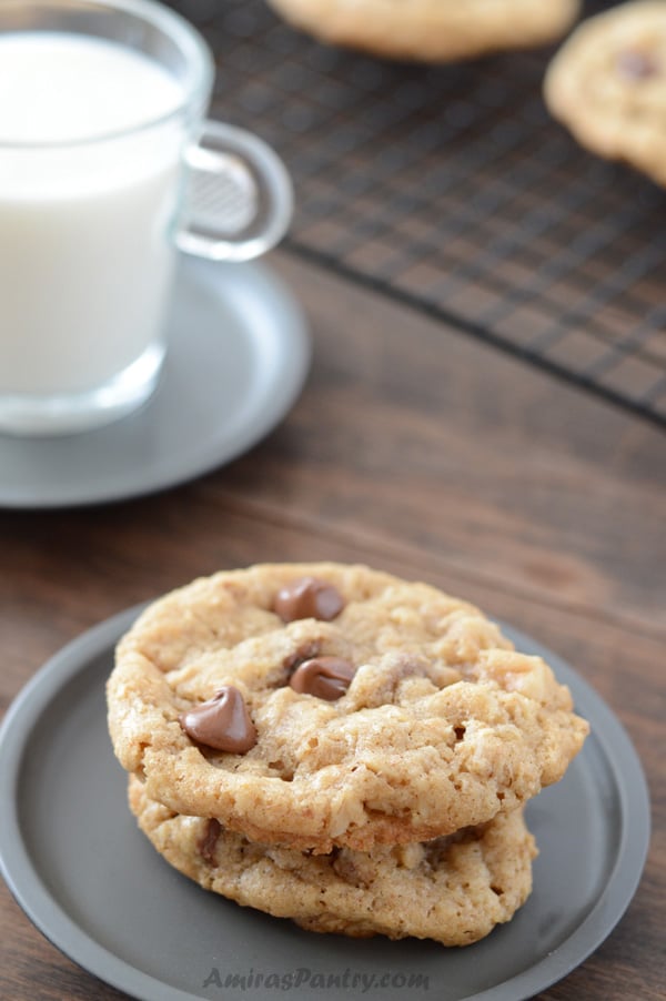 A close up of a plate of food and a cup of milk, with Oatmeal cookie