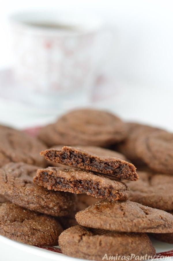 A soft and chewy molasses cookie cut in half and placed on a pile of molasses cookies.