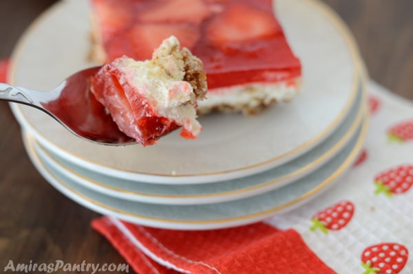 A fork holding up a bite of the strawberry pretzel salad.