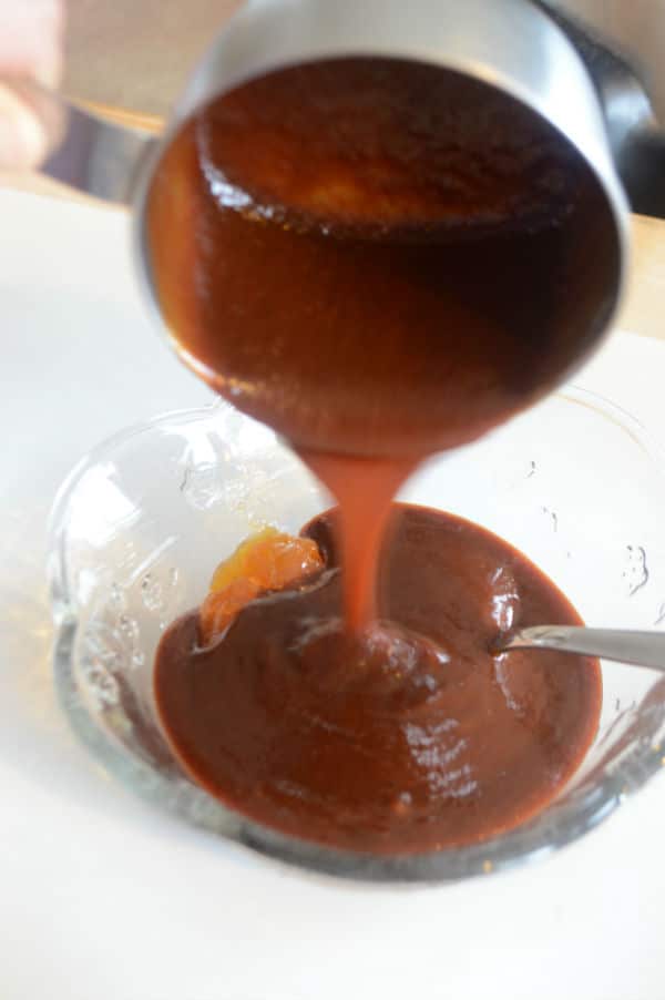 A close up of a glass cup with sauce being poured