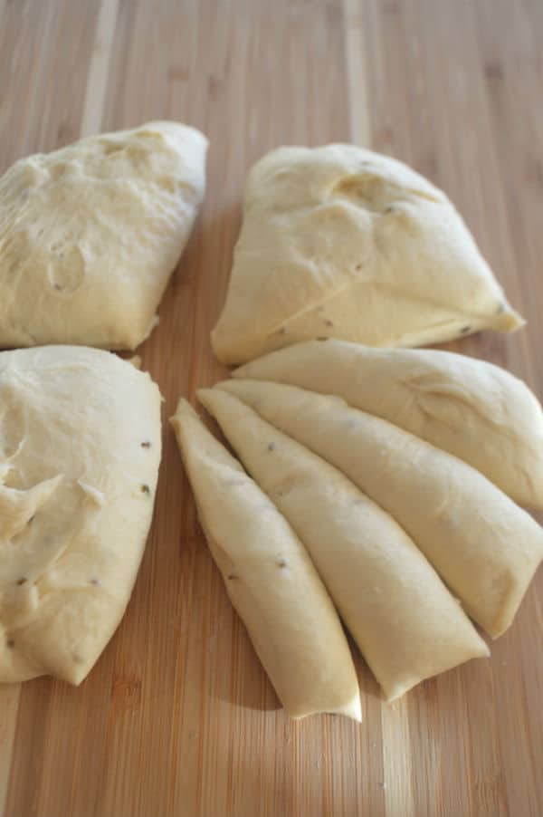 A wooden cutting board, with dough pieces sitting on top