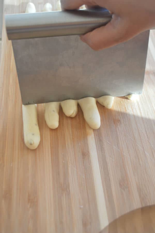 A wooden cutting board, with Breadstick being cut into pieces