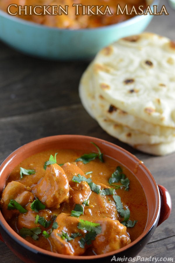 A bowl of food on a table with Chicken tikka and bread