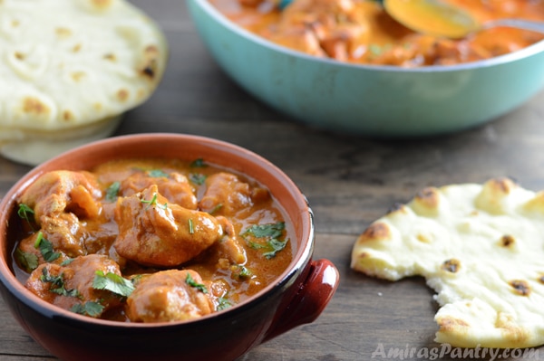 A bowl of food on a table with Chicken tikka and bread