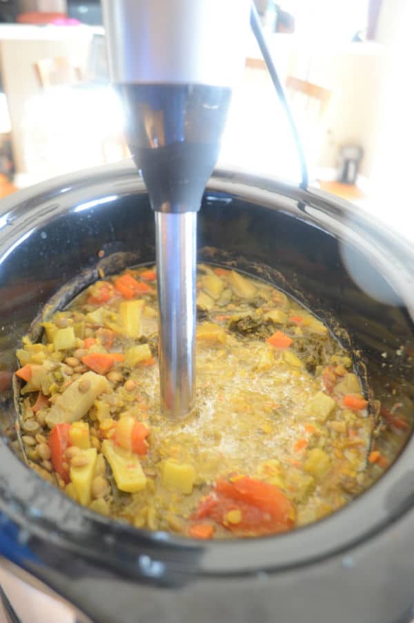 A bowl of food with vegetables and hand blender