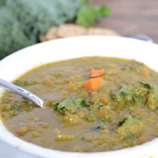 A bowl of soup, with kale and spoon