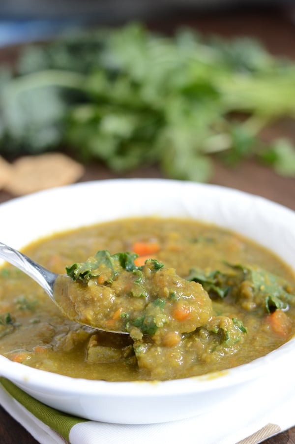 A bowl of food on a plate, with Kale Soup and spoon