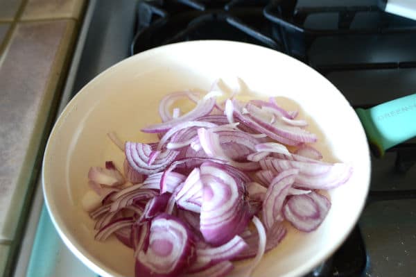 A bowl of food on a stove, with onions