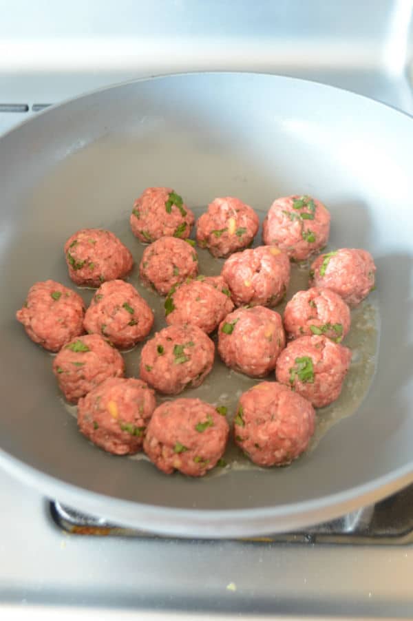 A bowl of food on a stove, with meatballs