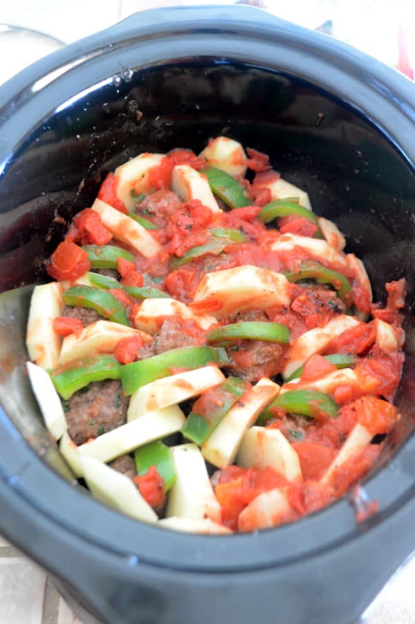 A bowl of food, with meatballs and vegetables