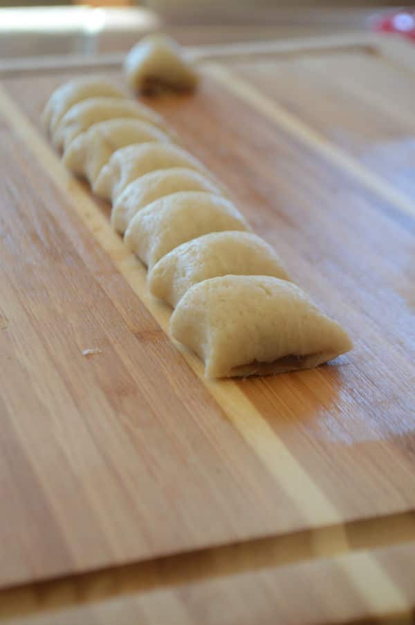 A wooden cutting board, with pieces of dough stuffed